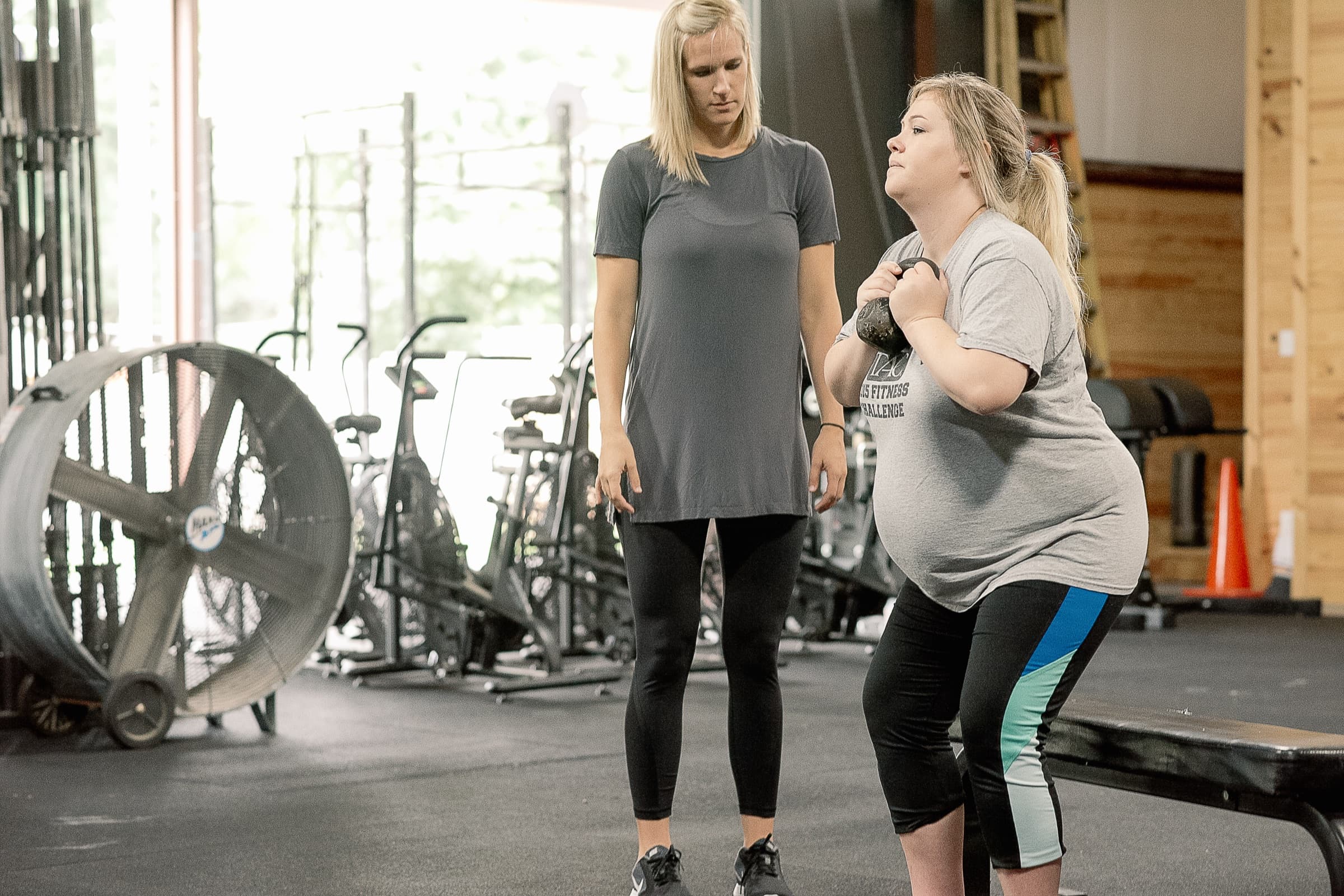 Physical therapist coaching a pregnant woman through a kettlebell exercise